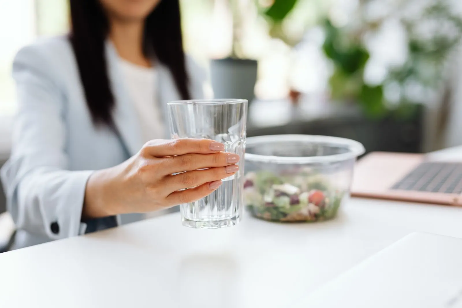 Ofiste masasında salata ve bir bardak su ile öğle arası veren çalışan